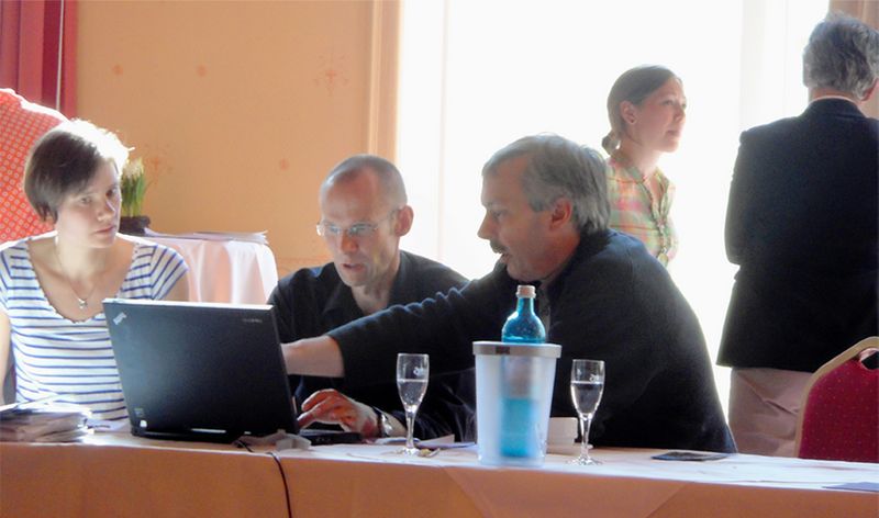 Several people discuss at a project meeting on a laptop